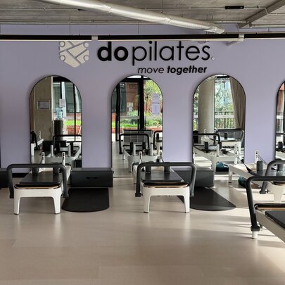 A reformer pilates studio with reformer beds and arched mirrors on a purple wall.