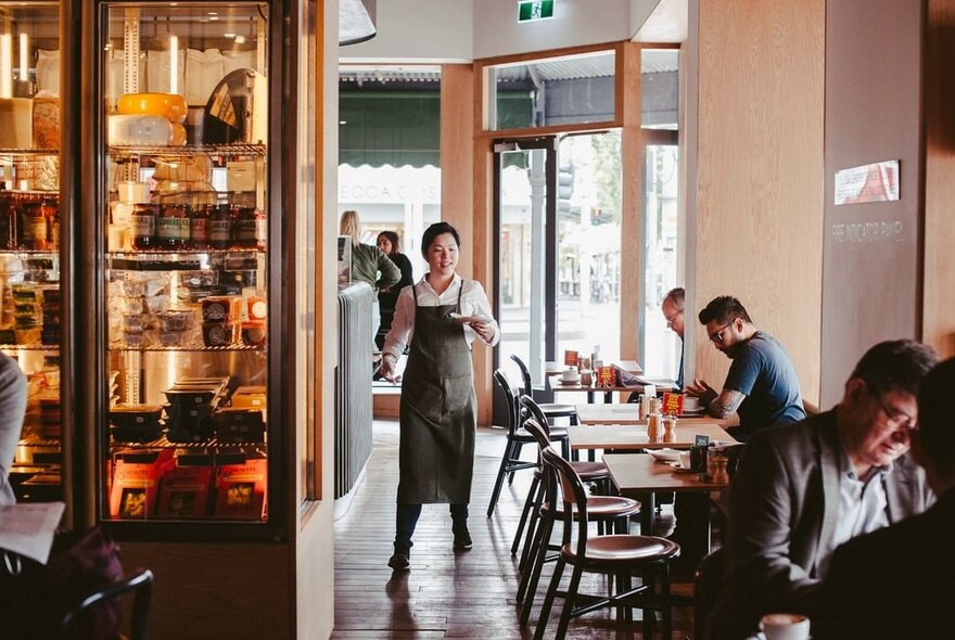 Waitress serving a drink and several customers seated in a cafe