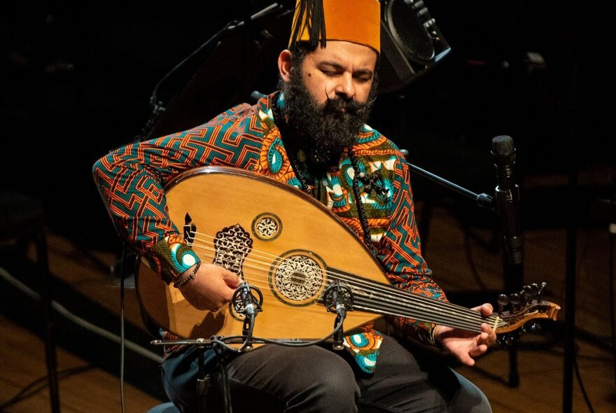 Joseph Tawadros playing an oud on stage.