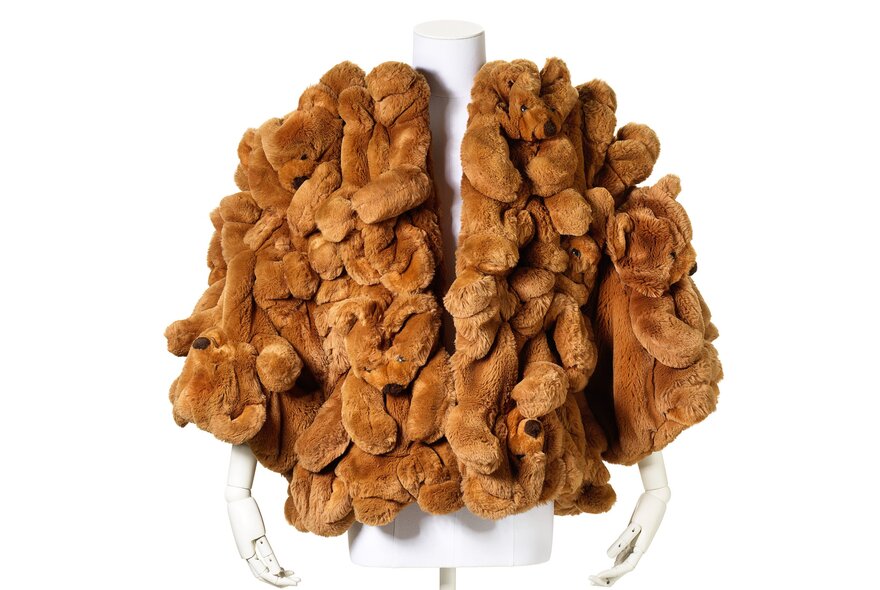 A tan jacket made of squiggly fur on a white dummy torso.