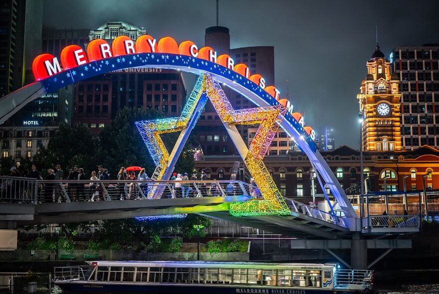 A giant star with a sign reading 'merry Christmas' over a city bridge at night.