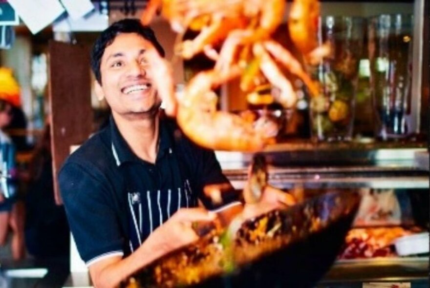 Happy chef tossing seafood in a wok.