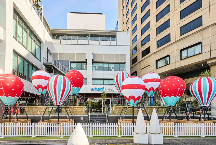 Outdoor dining space set up with basket booths and mini hot air balloons suspended above the tables, in front of The Wharf Hotel.