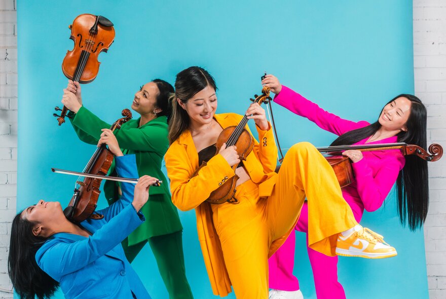 The four members of Invictus Quartet, each wearing a different coloured suit, posing with their instruments, against a green screen background.