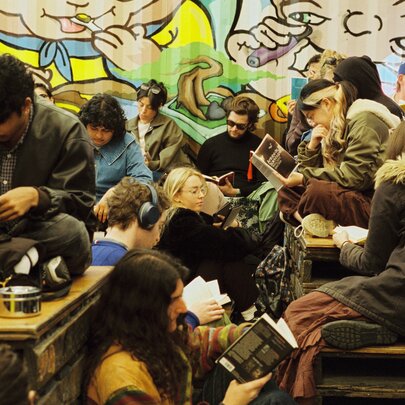 People gathered together reading books in an outdoor bar space. 