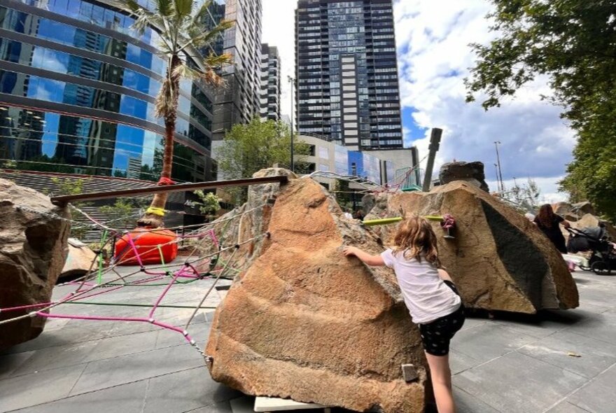Child climbing a big boulder at the Southbank Boulevard Play Space