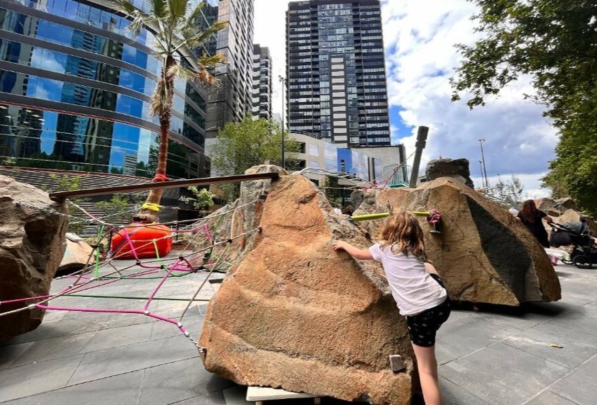 Child climbing a big boulder at the Southbank Boulevard Play Space
