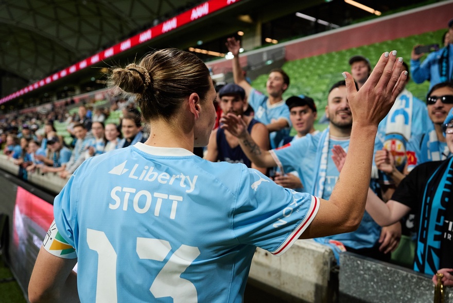 Soccer player clapping hands with fans in the stands.