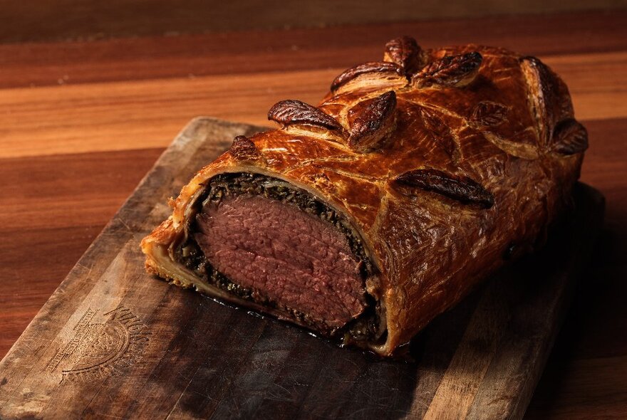 A beef Wellington on a wooden chopping board.