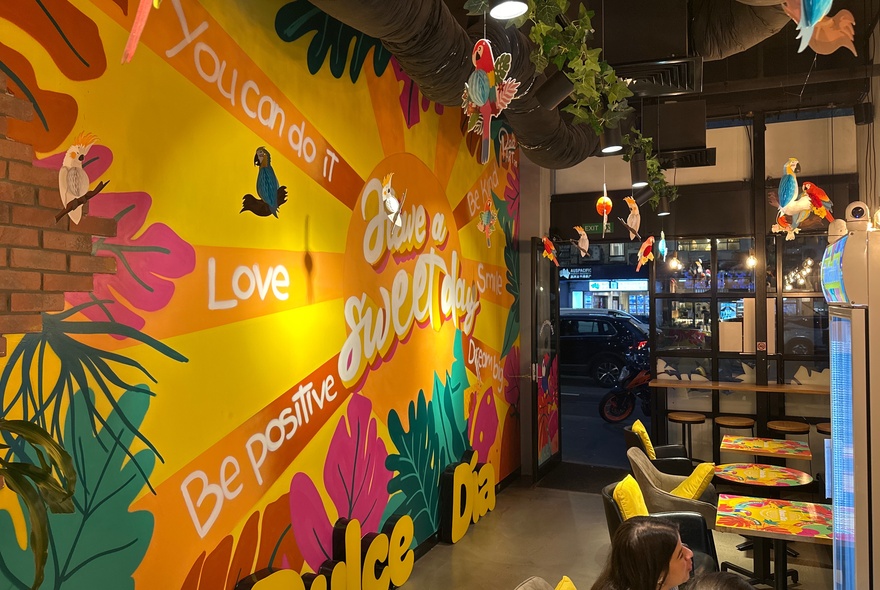 Colourful interior of a shop with a large painted mural on the brick wall.