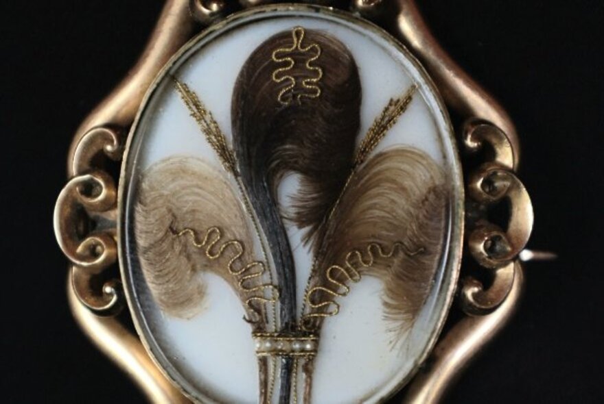 Victorian mourning brooch with decoratively styled snippets of hair in a curlicued gold setting.