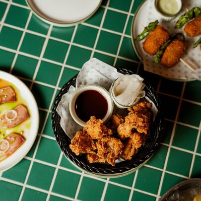 Looking down at bar snacks arranged on white plates on a green table.