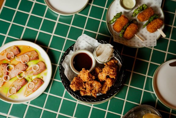 Looking down at bar snacks arranged on white plates on a green table.