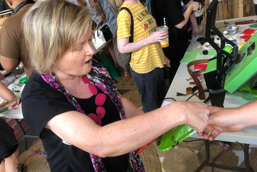 A person taking part in a workshop in a studio, and making a glasses case from soft plastic.