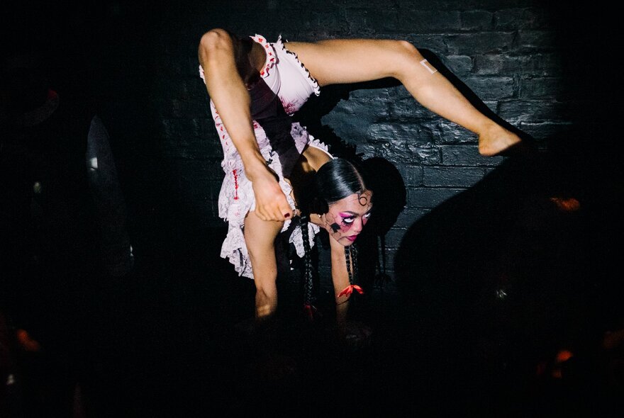 A burlesque dancer doing a handstand with her legs over the back of her head. 