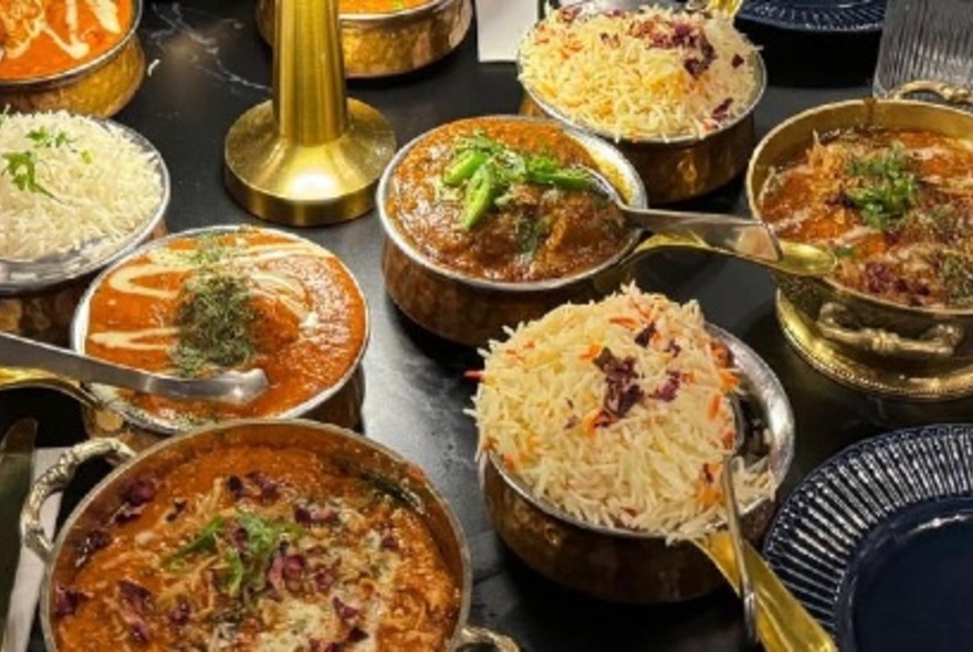 A delicious array of North Indian dishes, all presented in small metal pots with golden spoons.