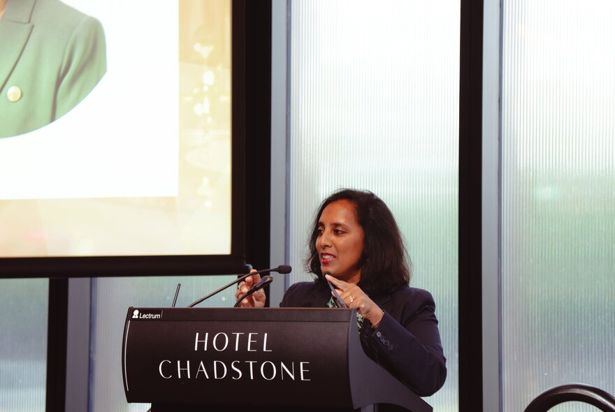 A woman speaking while standing behind a podium.