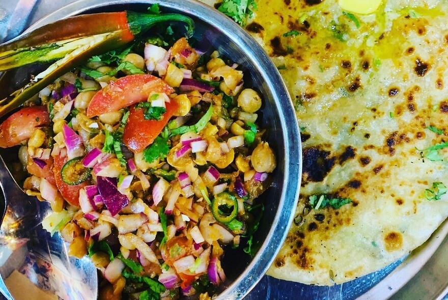 A close-up of a plate of Indian food with naan.