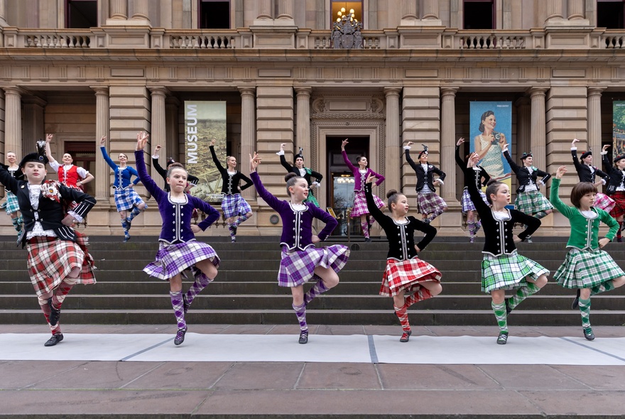 Dancers wearing kilts performing Scottish Highland dancing on the steps of Old Treasury Building.