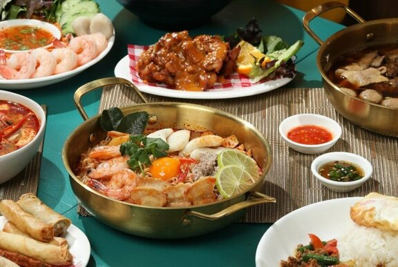 A table set with lots of Thai dishes.