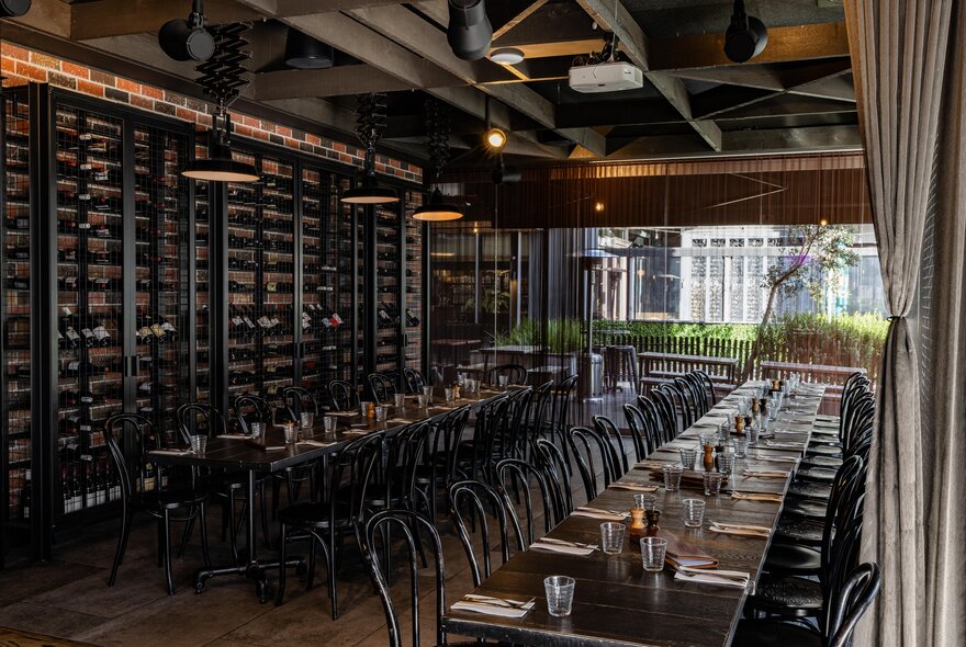 Interior of Soho Restaurant & Bar with two long rows of tables and chairs, a wall of wine bottle and floor to ceiling windows at the rear.