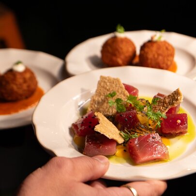 Colourful fresh entrees of raw fish and croquettes on white plates 
