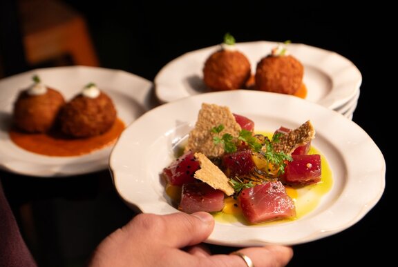 Colourful fresh entrees of raw fish and croquettes on white plates 