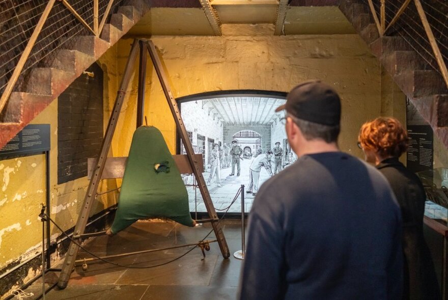 The back of two people looking at an exhibit in the Old Melbourne Gaol. 