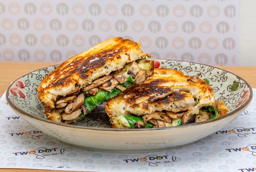 A mushroom toastie, halved in a bowl. 