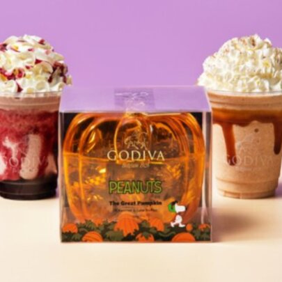 Two cream-topped drinks next to a plastic orange gift box.