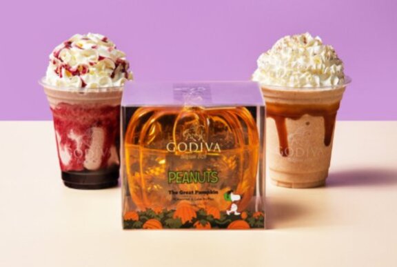 Two cream-topped drinks next to a plastic orange gift box.