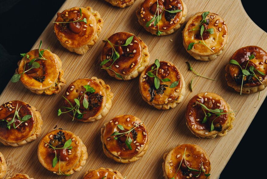 A wooden board with small pastry canapes.