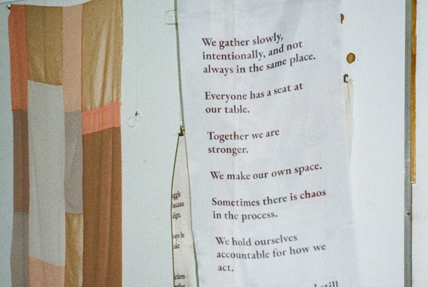 A white poster taped up on a wall with illegible black typed text. 