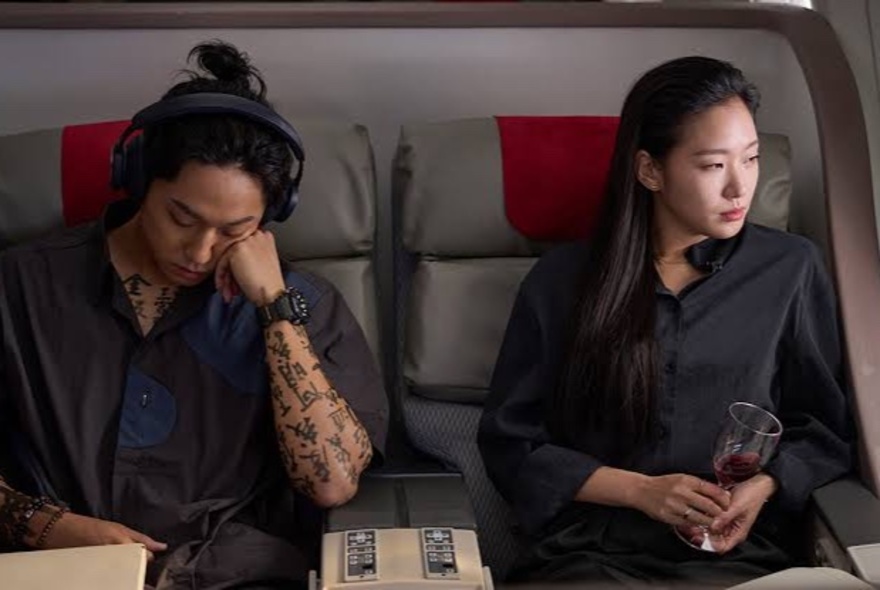Two people sitting next to each other on an airplane, a scene from the movie Exhuma.