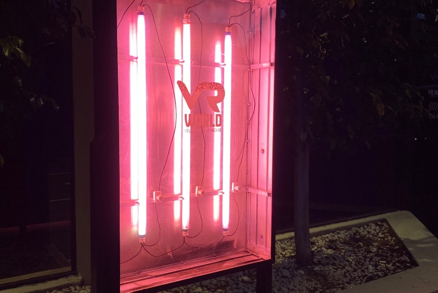 Three vertical pink neon lights in a dark room. 