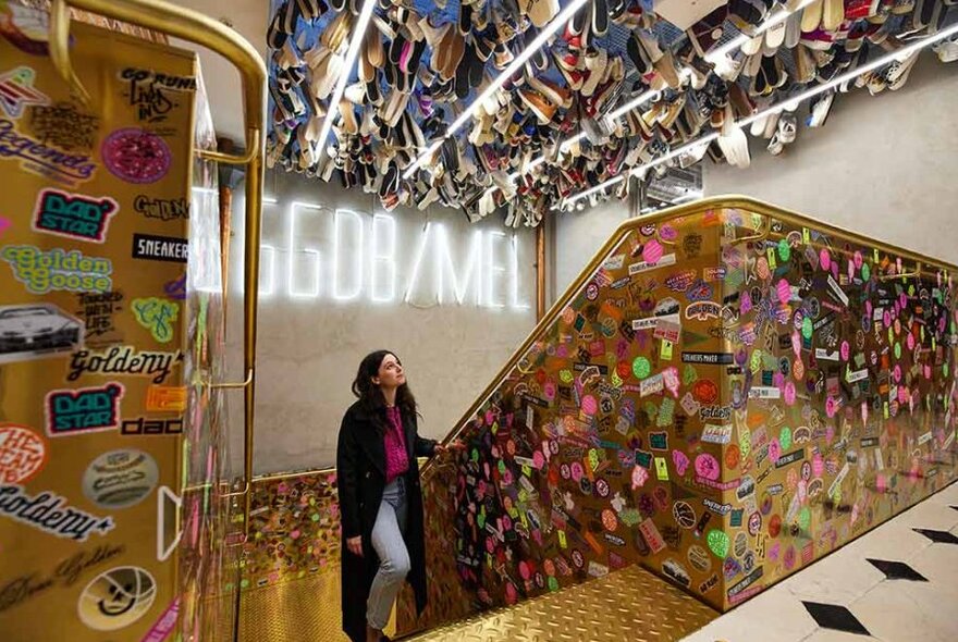 A girl walking up golden sticker covered stairs looking up