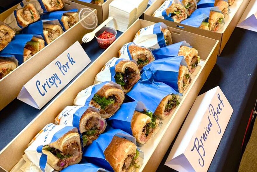 Rows of banh mi sandwiches wrapped in blue paper.