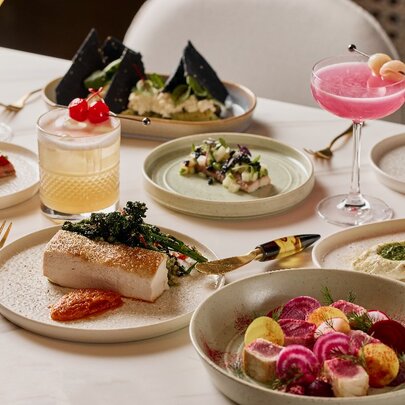 Restaurant table set with a range of dishes and cocktail drinks.