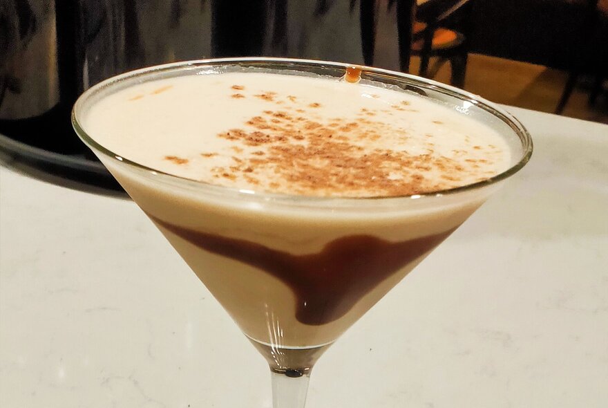 A milky cocktail in a martini glass with sprinkles.