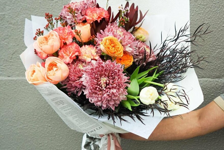 Hands holding a bunch of pink flowers.