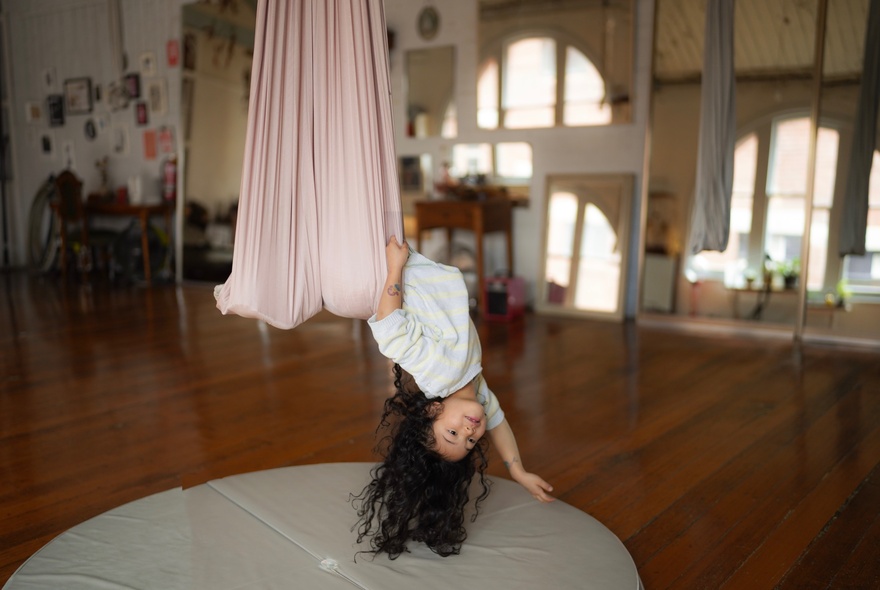 Child suspended upside-down from an aerial suspension cloth.