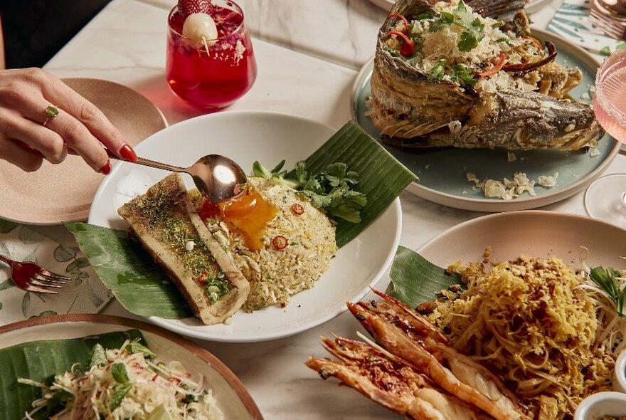 Plates of rice and bone marrow, a whole fish and prawns