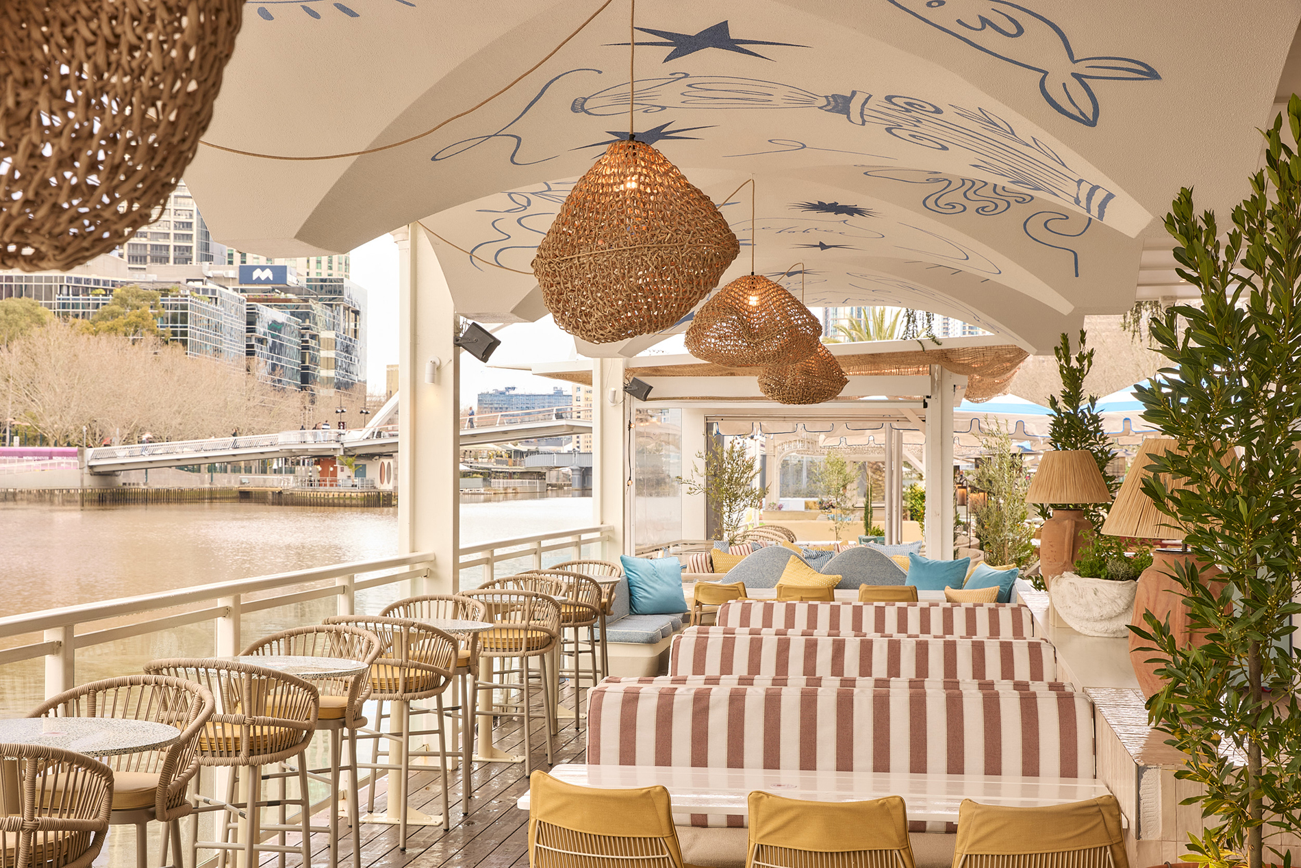A floating bar with stripy booth seats and wicker pendant lights.