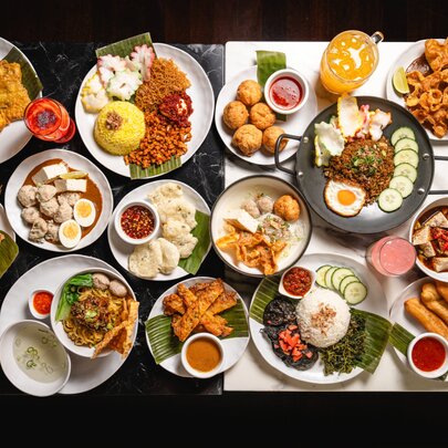 Overhead view of multiple Indonesian dishes of food including fried and salad dishes.
