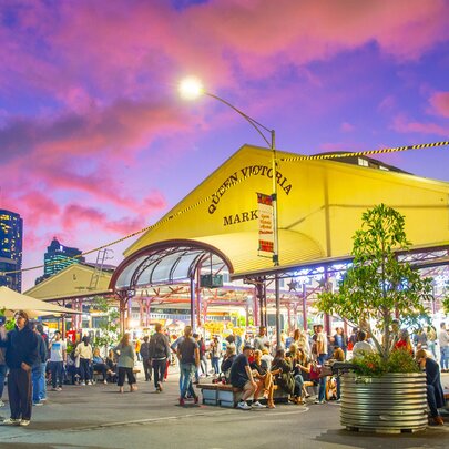Crowds milling around the Vic Market sheds at sunset.