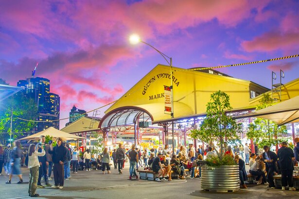 Crowds milling around the Vic Market sheds at sunset.