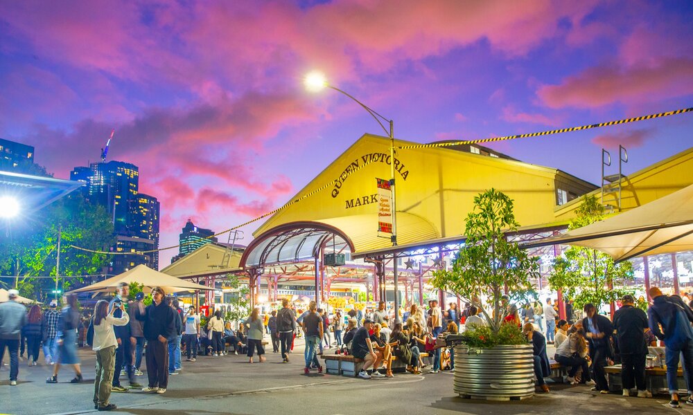 Crowds milling around the Vic Market sheds at sunset.