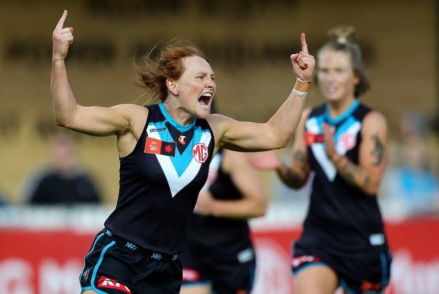 Port Adelaide AFLW football player screaming during a match with both arms raised pointing a finger into the air.