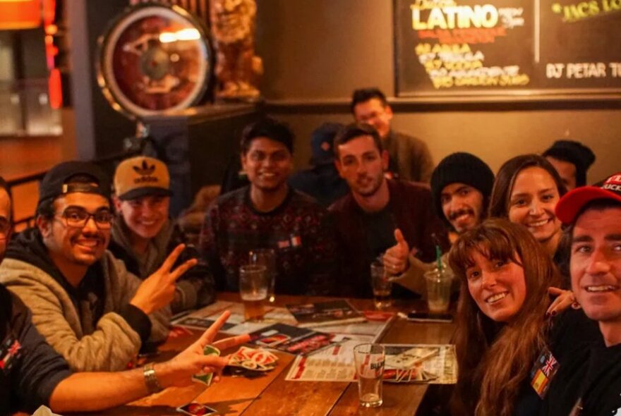 Group of smiling people sitting around a table in a pub.