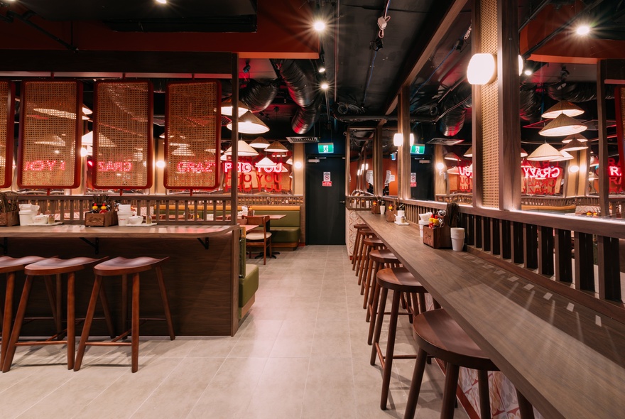 An empty restaurant with stools on narrow counters and warm tones. 